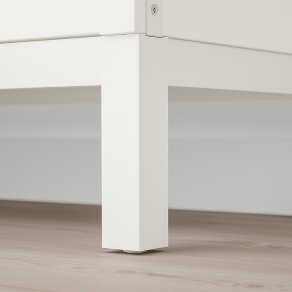 White tv stand leg with metal fixtures on light wood floor.
