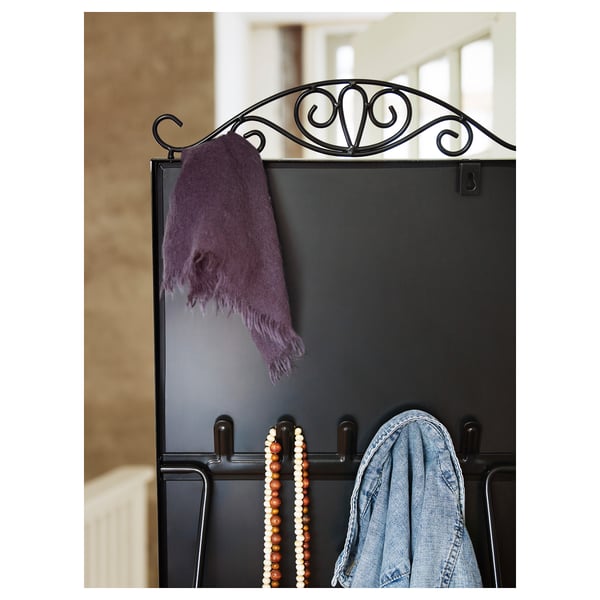A black mirror with hooks holds a purple scarf, colourful beads, and a denim jacket, reflecting a stylish organisation setup.