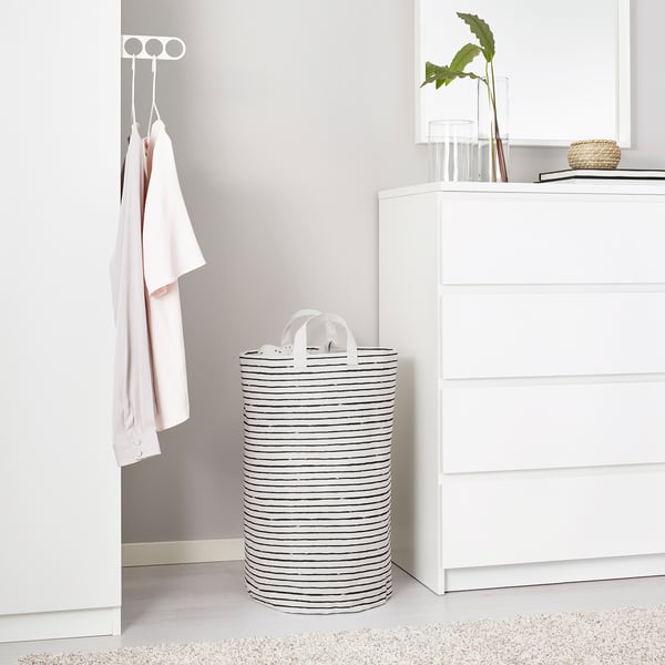KLUNKA laundry basket, black/white, between dresser & clothes. Cylindrical, striped fabric/plastic, handles top.
