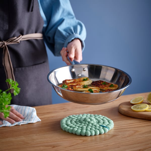 Person cooks in frying pan with lemon and cloth.