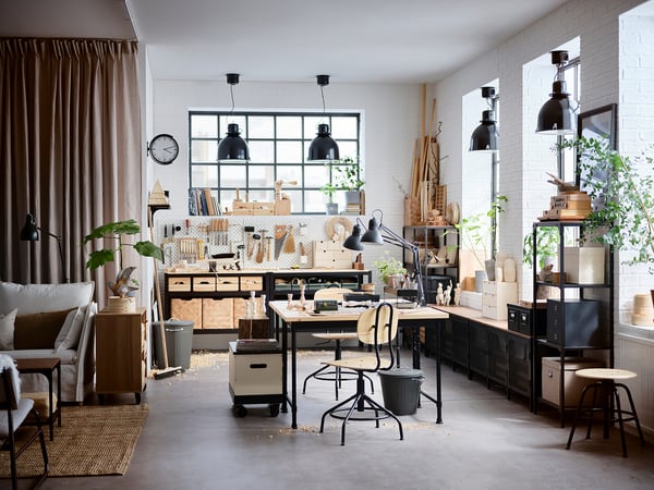 Spacious workshop with KULLABERG desk, plants, and black lamps, offering a blend of natural wood and modern style.