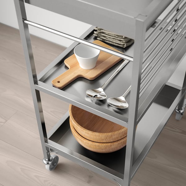 Modern stainless steel kitchen cart with wheels, featuring utensils, cutting board, and bowls, perfect for food prep in small spaces.