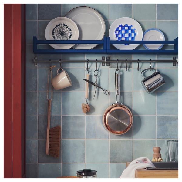 KUNGSFORS blue shelf with white plates, hanging cups, pans, and brushes. Modern, functional kitchen storage.