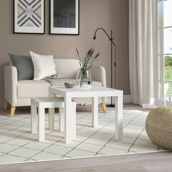 Modern living room with white LACK table, greenery, and decor; white couch, lamps, and rug.