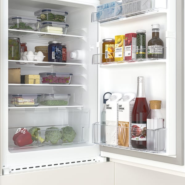 A well-organized mini fridge with transparent compartments, showing fresh vegetables, jars, and drinks. Adjustable shelves maximise storage.