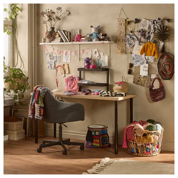 Creative craft room with LAGKAPTEN desk, colourful yarn, knitted items, and plants.