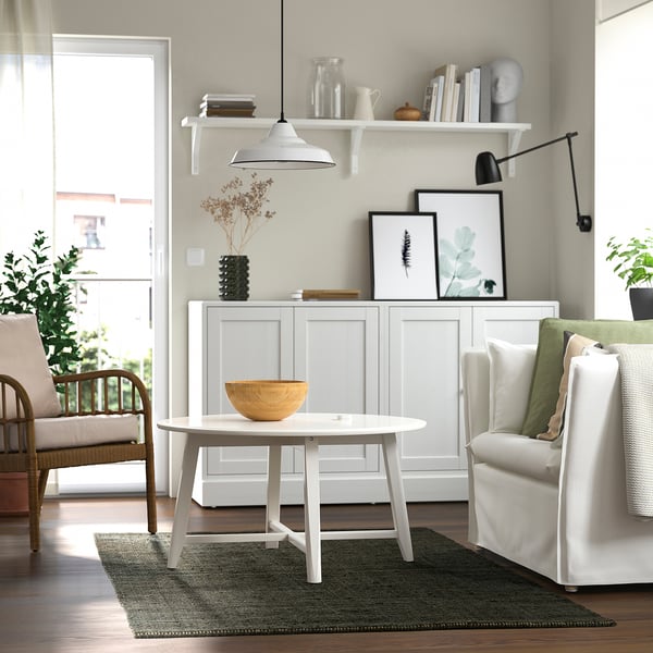 Modern living room with LANDBANA jute rug, dark green, white furniture, plants, pictures, hanging light.