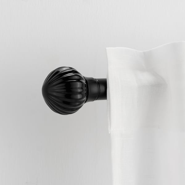 A black LERBRONIA finial for a curtain rod. Its small, round, and textured, mounted on a white curtain.