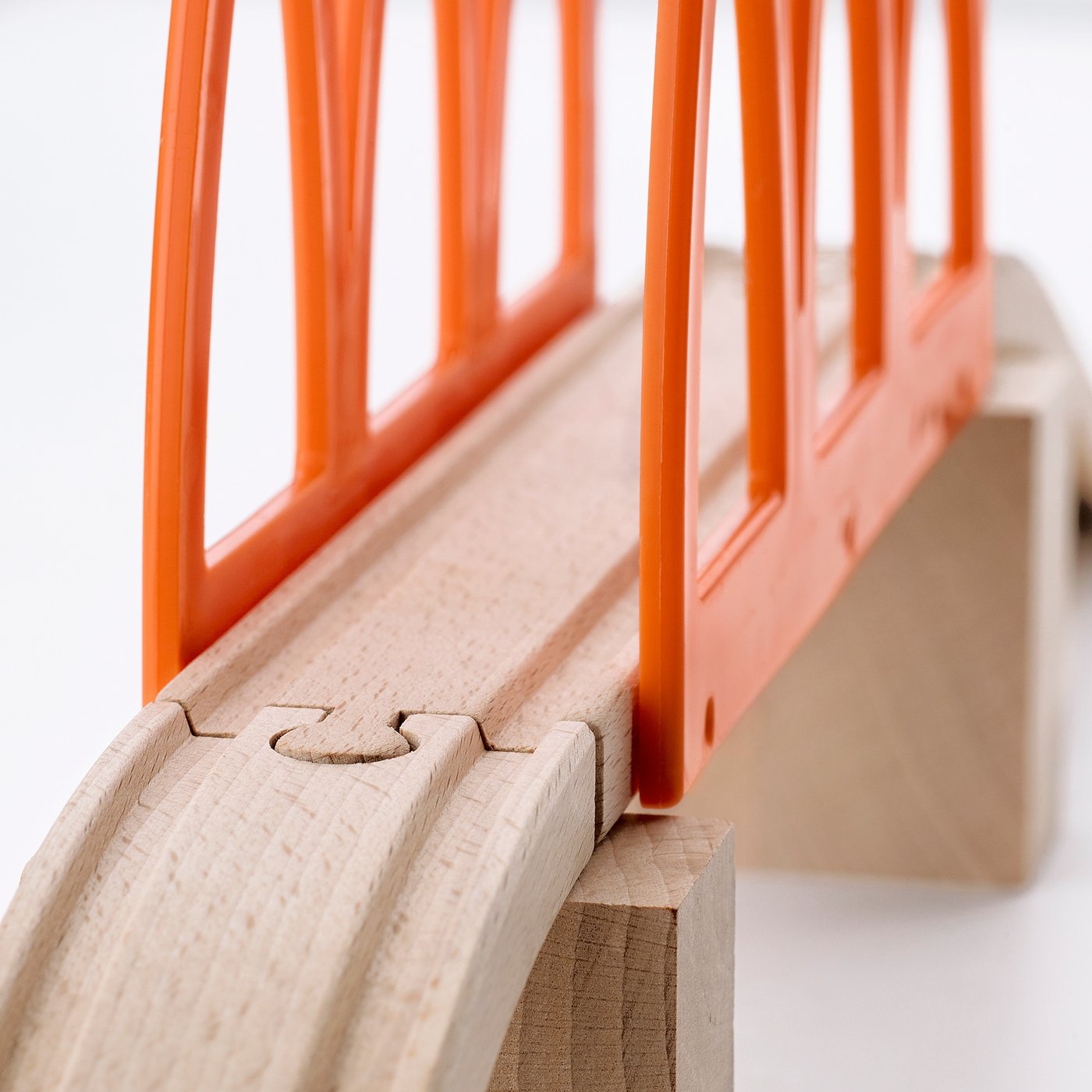 Close-up of high-quality wooden train track with orange plastic bridge, showcasing durable craftsmanship.