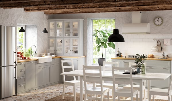 Modern kitchen with grey METOD cabinets, wooden countertops, white dining set, stainless steel appliances, and black pendant lights.