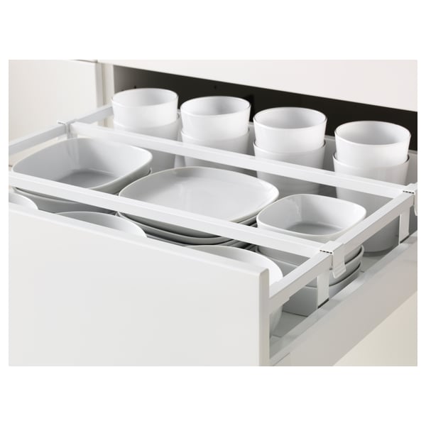 White kitchen drawer organiser with multiple compartments holding white ceramic bowls and cups, showcasing efficient storage solution.