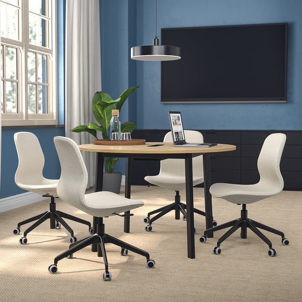 MITTZON conference table with white chairs in a cosy workspace with tv and window.