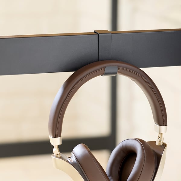 Brown leather headphones hang on black stand.