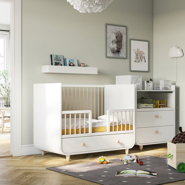White MYLLRA crib with wooden accents in cosy nursery.