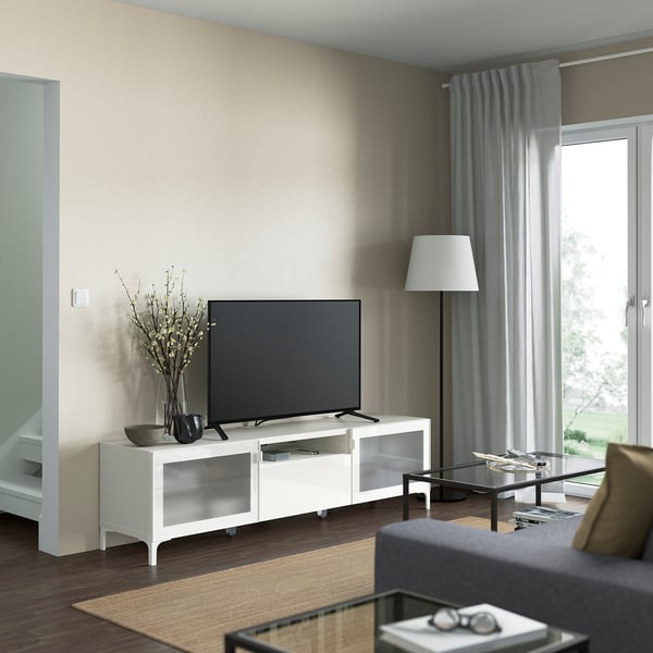 Living room with white NANNARP tv stand, black tv, floor lamp, gray curtains, gray sofa, and glass coffee table.