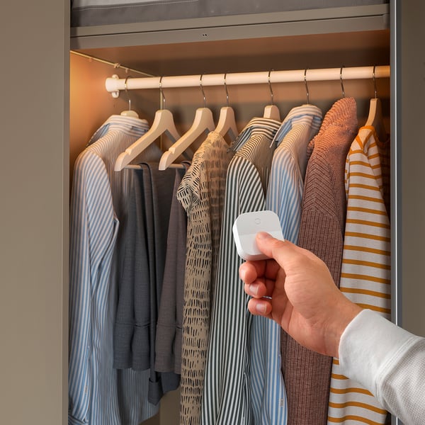 Person turns closet light, highlights clothes.