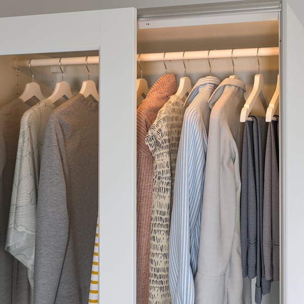 Well-organized wardrobe with led lights, illuminating clothes on hangers.