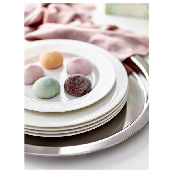 Stack of white porcelain plates, featuring five colourful rounded candies on top plate, displayed on metallic tray, perfect for serving treats.