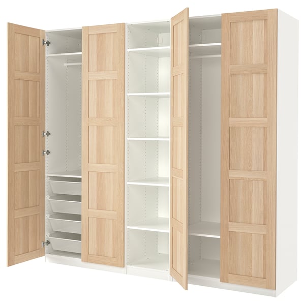 An open IKEA PAX wardrobe with light wood panels and white interiors, showcasing shelves and drawers.