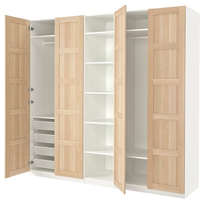 An open IKEA PAX wardrobe with light wood panels and white interiors, showcasing shelves and drawers.