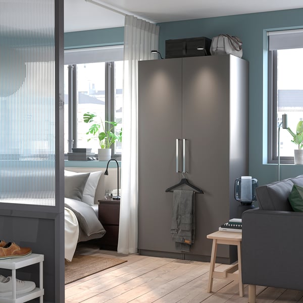 Minimalist bedroom with grey PAX wardrobe & sofa. Sleek decor.