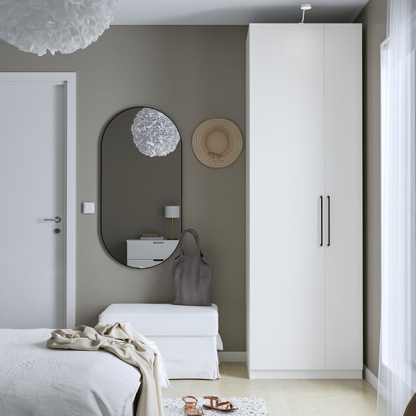 Modern bedroom with white PAX wardrobe, mirror, and minimalist decor.