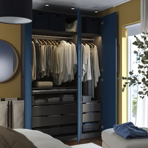 Modern bedroom with blue PAX wardrobe showing hangers, drawers, and interior organisers.