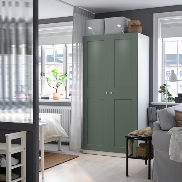 Modern bedroom with green PAX wardrobe, large windows, cosy bed and plant.