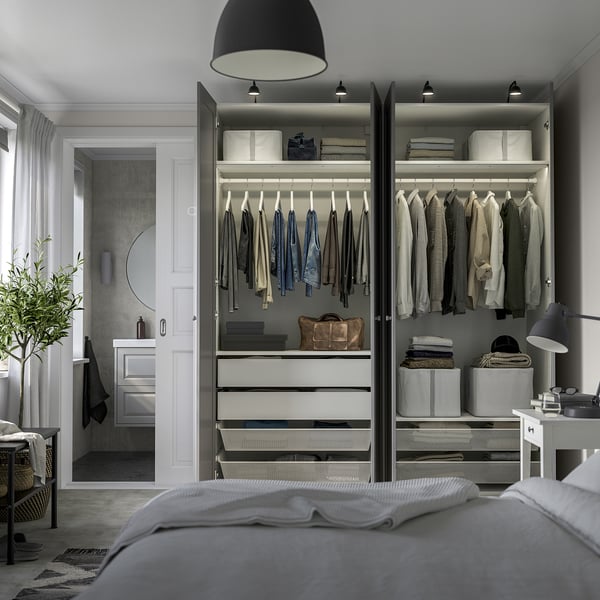 Modern bedroom with organised open wardrobe. Clothes hung neatly, drawers below, integrated lighting.
