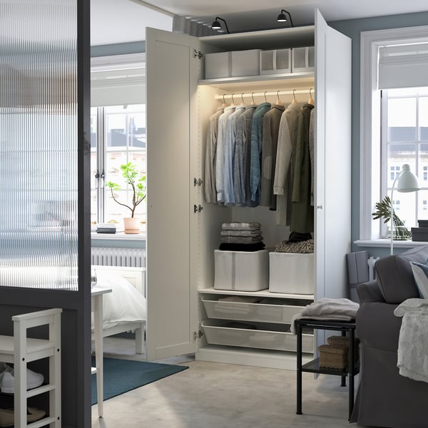 Open wardrobe with clothes, organised shelves, and storage boxes. Integrated lighting illuminates the closet space.