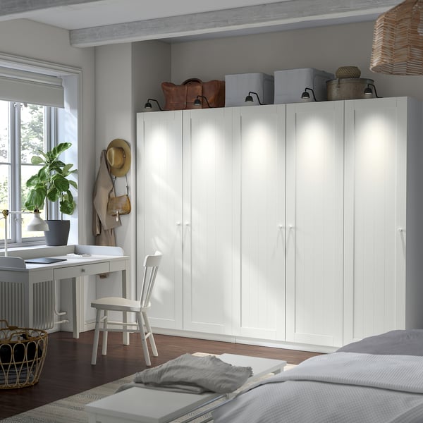 Large white wardrobe beside desk, topped with storage.