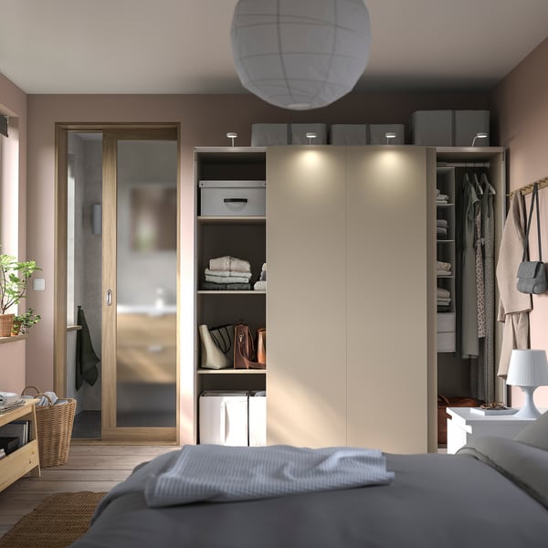 Modern bedroom with PAX wardrobe, sliding doors, shelves, lighting, lamp, plant.