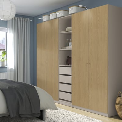 Brown PAX wardrobe in bedroom, with shelves, drawers, & wall baskets.