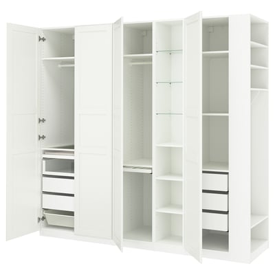 A white IKEA PAX wardrobe with open doors, revealing shelves and drawers inside.