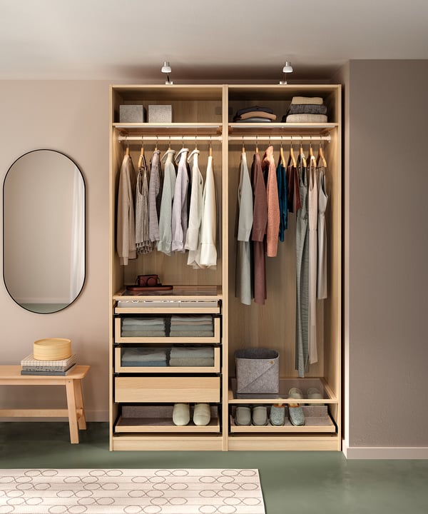 Organised PAX wardrobe in light wood; hangers, shelves, glass drawers.