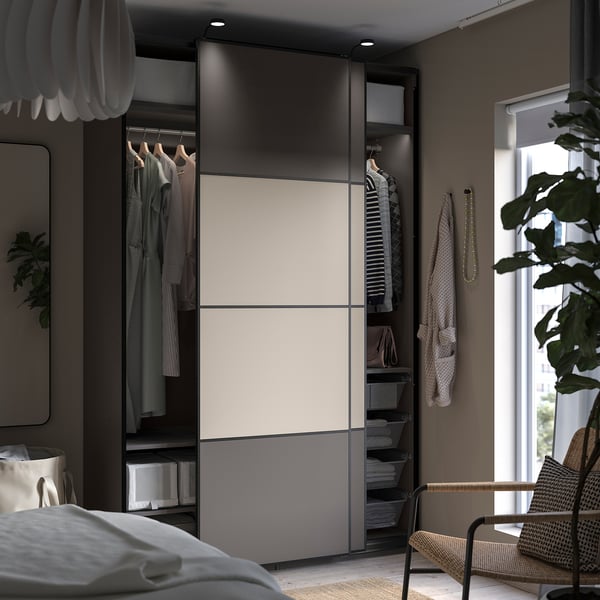 Bedroom with PAX wardrobe, hanging clothes, shelves, baskets & wicker chair by window.
