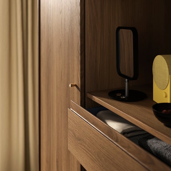 Wooden wardrobe with sliding door, gold handle, black lamp & yellow speaker.