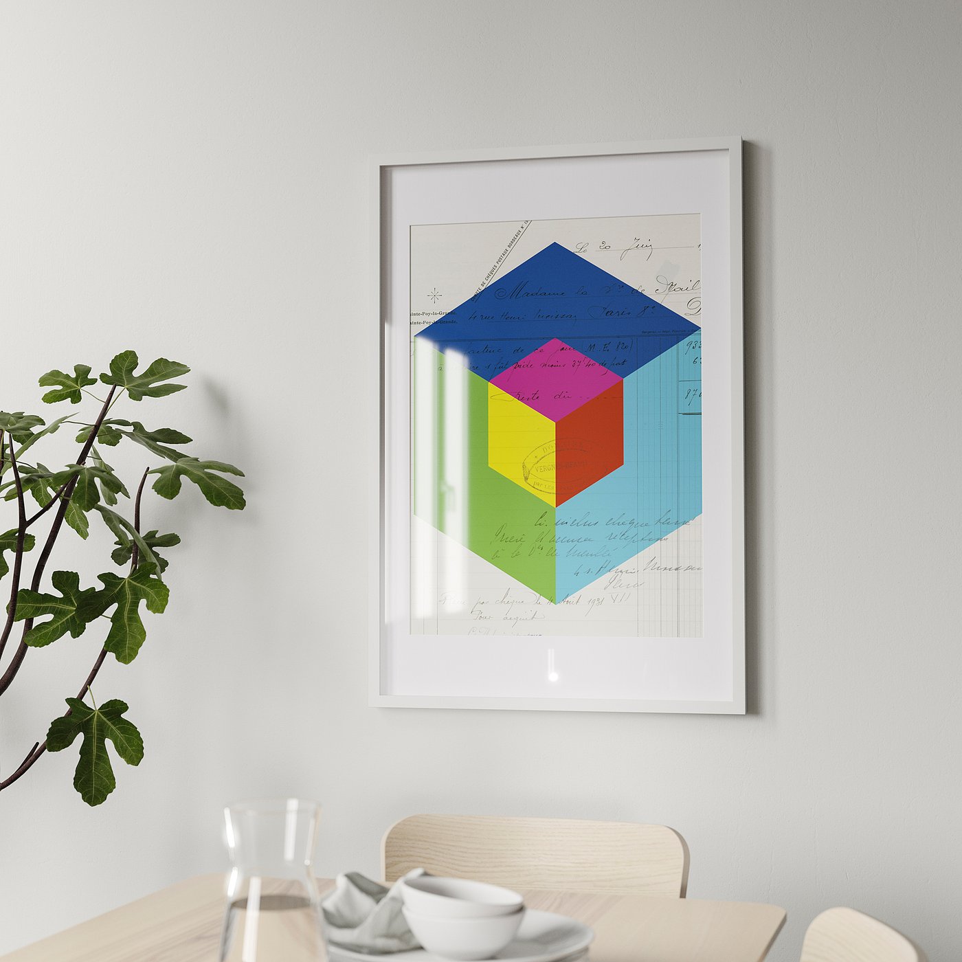 Multicoloured geometric art in white frame above dining table with white tableware and plant.