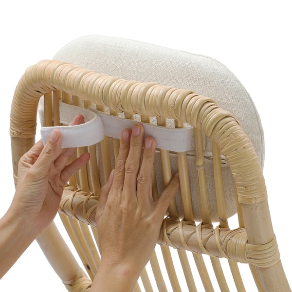 Person is assembling a woven rattan chair, inserting a cushion with foam.