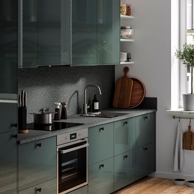 Modern kitchen with dark grey wall panels, oven, sink, plant, and wooden boards.