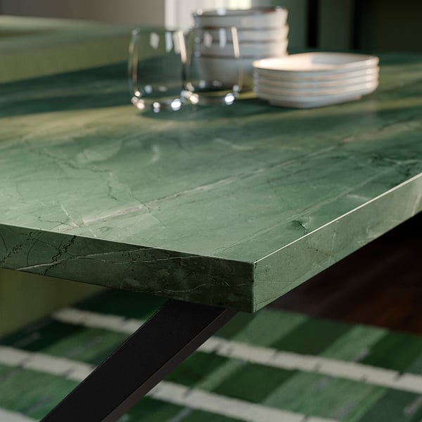 Close-up of sleek, polished green tabletop with visible veins, supported by metal legs.
