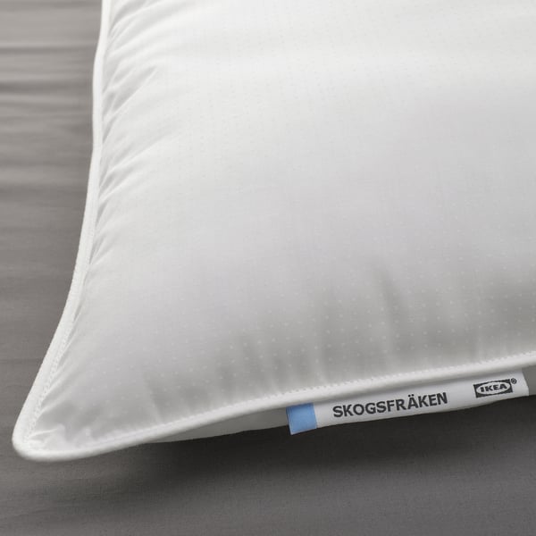 Close-up of a white IKEA SKOGSFRÄKEN pillow on a bed, showcasing its smooth, supportive fabric, and brand tag at the corner.