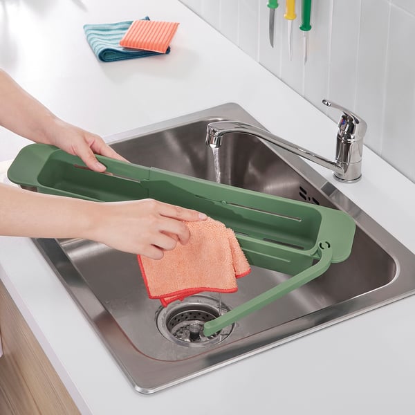 Green skola sink organiser with cloth, dishcloth, and metallic sink drain.