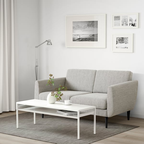 Sofa in modern living room with lamp, coffee table, and flowers.