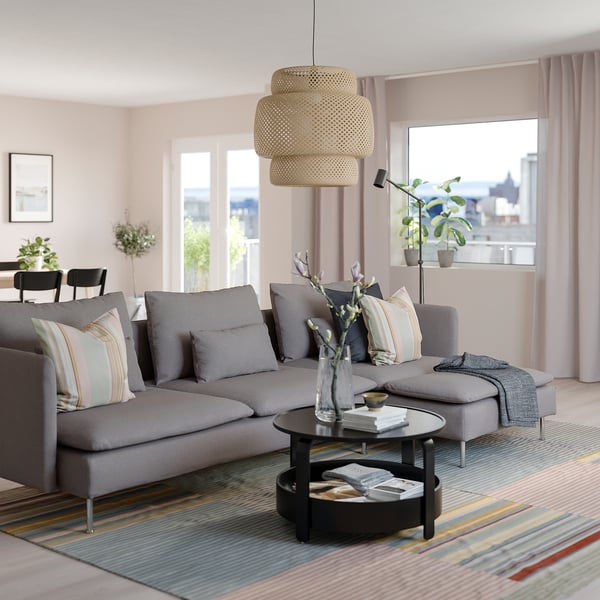 Modern living room: grey SÖDERHAMN sectional sofa, striped pillows, round coffee table, stylish pendant lamp, large window with city view.