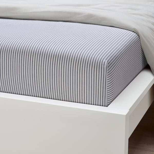 Bed with grey striped fitted sheet on white frame.