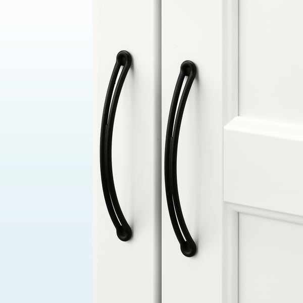 Black curved handles on white cabinet doors, sleek and minimalist design.