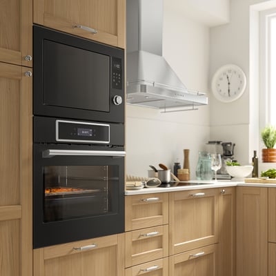 Modern kitchen with black IKEA STENABY oven, built-in microwave, wooden cabinets, and various countertop appliances and utensils.
