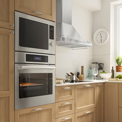 Modern kitchen with stainless steel double oven & microwave from IKEA. Sleek, functional design with digital controls and air fry option.