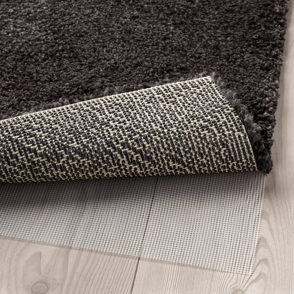 Close-up of thick, grey area rug with anti-slip mat underneath for stability.